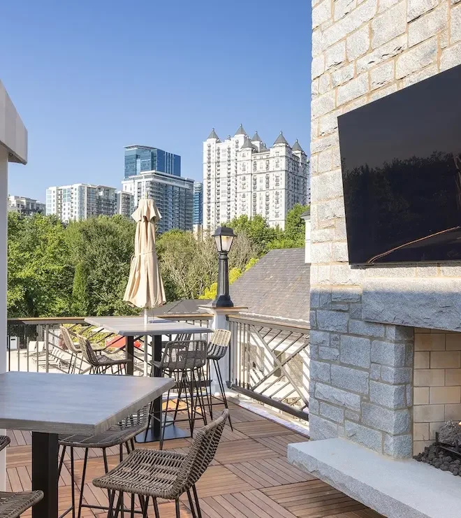 Outdoor patio at a private club featuring a wall-mounted weatherproof TV above a stone fireplace installed by Macrotek Services.