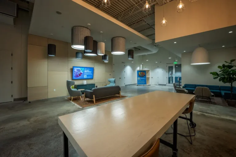 Modern church lobby with lounge seating, pendant lights, and a wall-mounted digital signage display