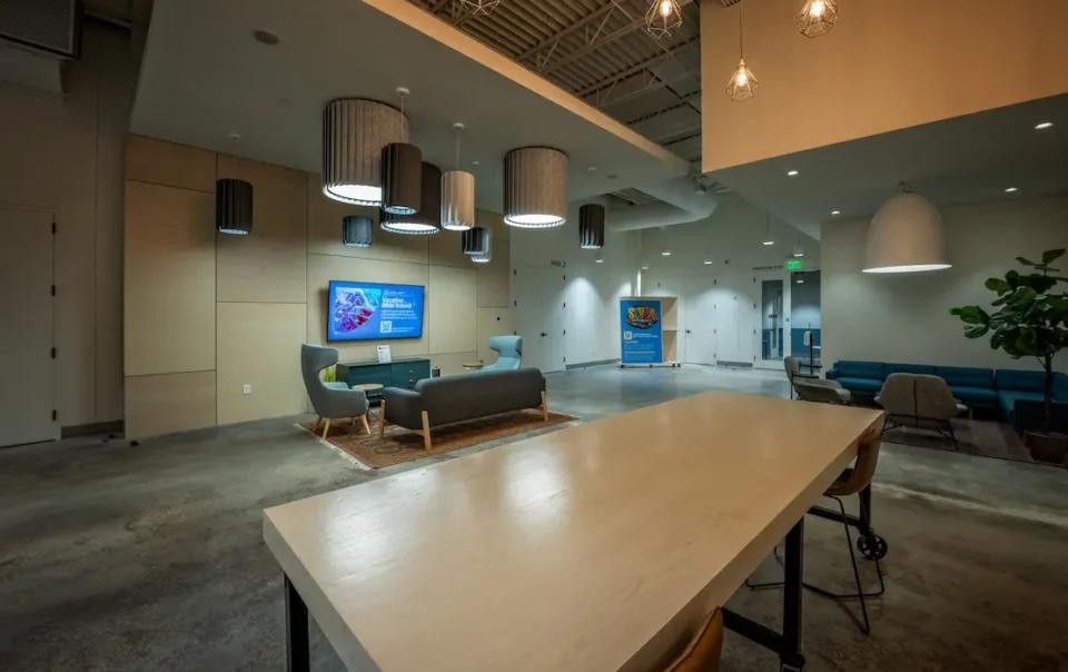 Modern church lobby with lounge seating, pendant lights, and a wall-mounted digital signage display