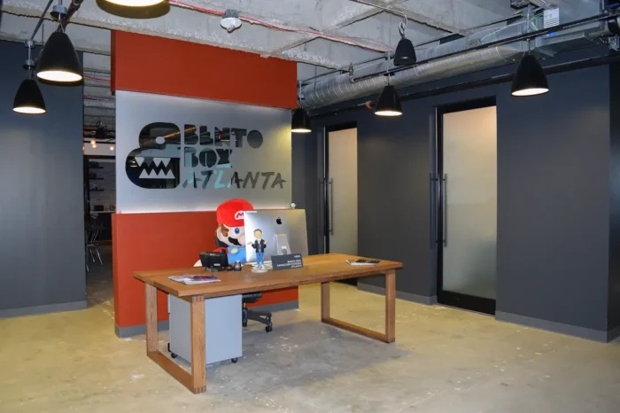 Reception desk at Bento Box Atlanta with Mario plush and AV-integrated workspace designed by Macrotek Services