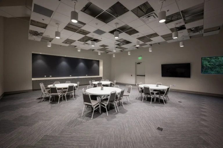Large multipurpose classroom at Atlanta Westside Presbyterian Church featuring round tables, modern lighting, and a wall-mounted display installed by Macrotek Services.