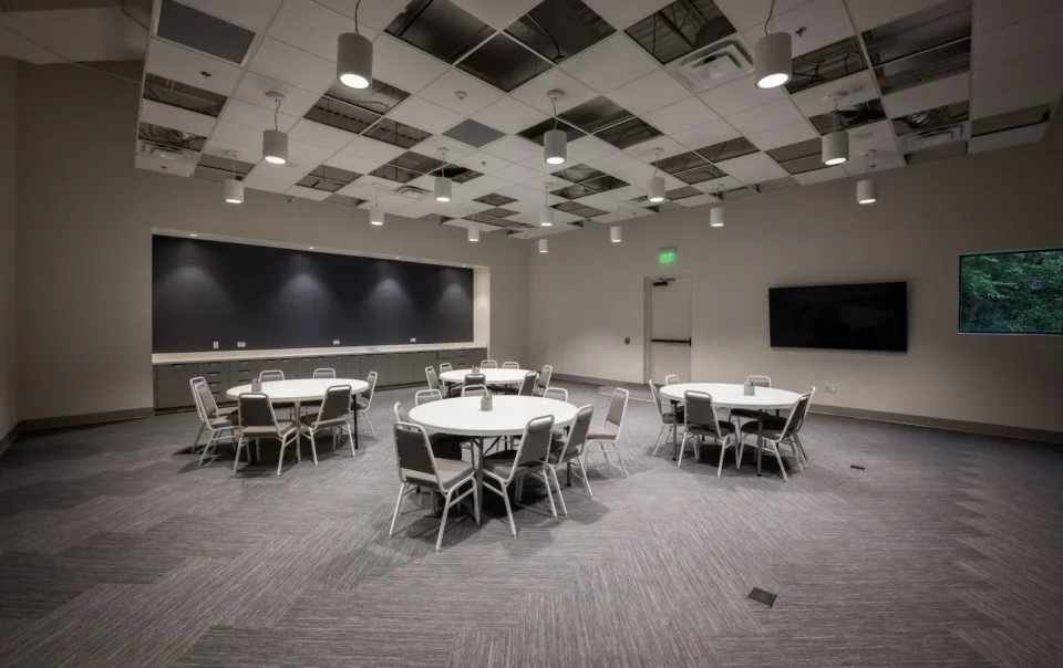 Large multipurpose classroom at Atlanta Westside Presbyterian Church featuring round tables, modern lighting, and a wall-mounted display installed by Macrotek Services.