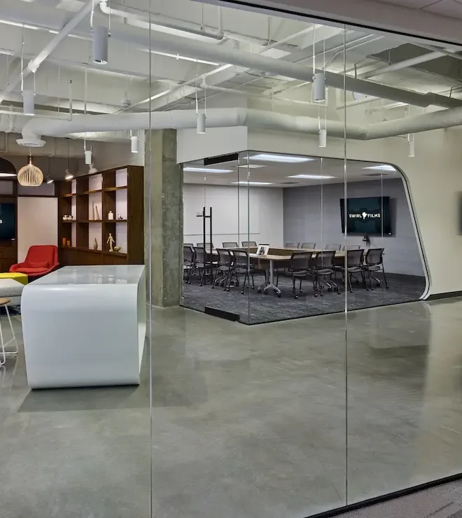 Modern office with glass-walled conference room and media lounge featuring multiple displays installed by Macrotek for Swirl Films.