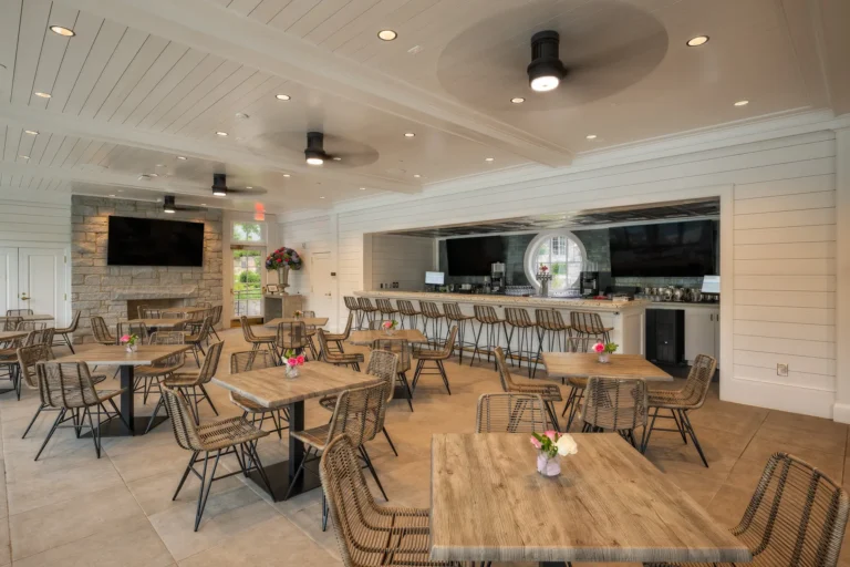 Casual dining room with bar, mounted displays, and woven chairs at a private club