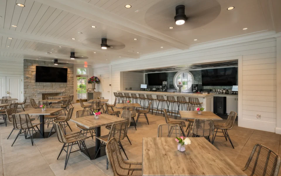 Casual dining room with bar, mounted displays, and woven chairs at a private club