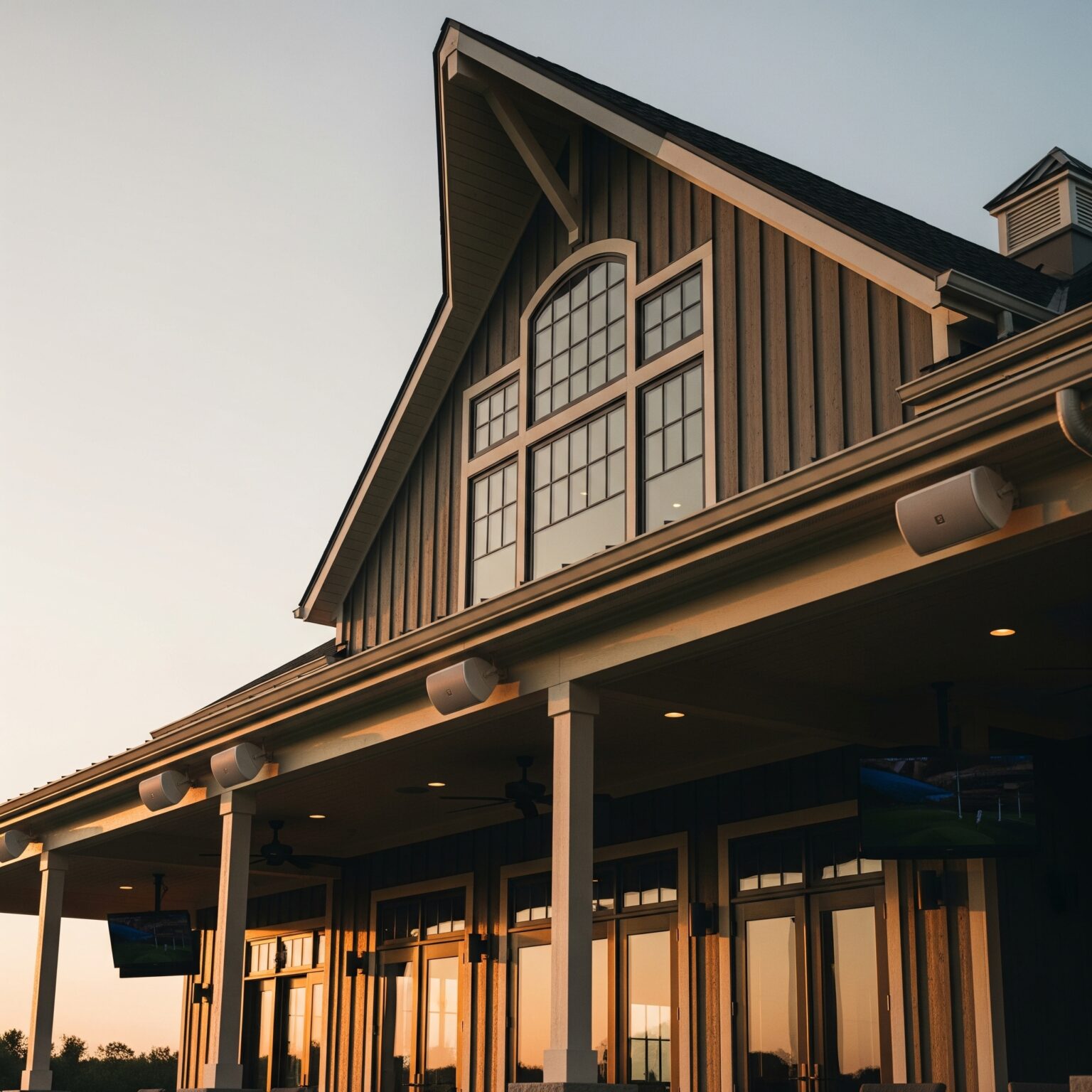 Modern country club exterior with integrated outdoor AV system and mounted speakers at sunset