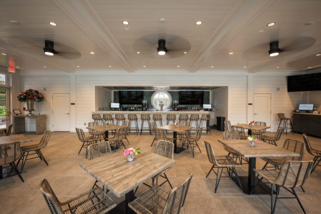 Bright country club dining area with integrated dual-display AV system and modern bar seating
