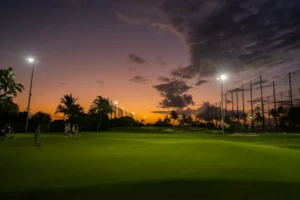 Practice area with distributed audio system along driving range illuminated at twilight